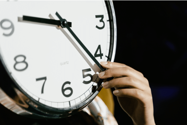 Femme qui déplace les aiguilles de l'horloge, comme si on pouvait maîtriser le temps.