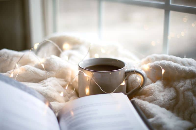 Les plaisirs de l'hiver peuvent aussi passer par des activités à l'intérieur et des petits moments de bonheur comme prendre un bon café et lire un livre dans le confort de son foyer. Un article du blog Pour un bonheur simple.
