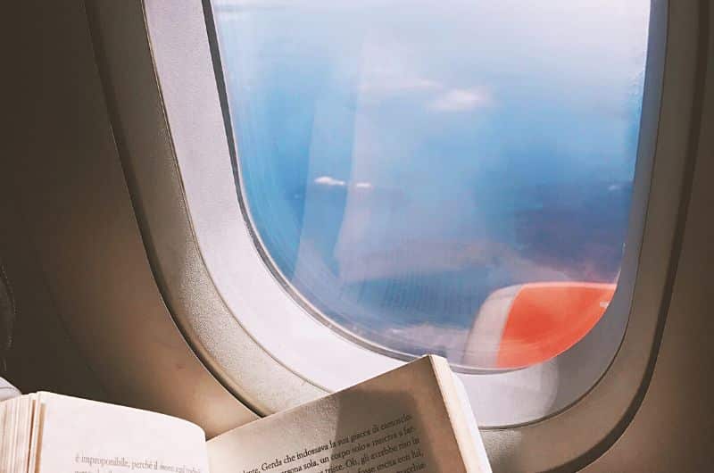 Cette image du hublot d'un avion, avec le coin d'un livre, nous rappelle que lire est une activité agréable à faire en vol. Alors, on met un joli bouquin dans son bagage à main? Au soutien d'un article du blog Pour un bonheur simple.